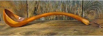 Long-handled wooden soup ladle on a weathered board